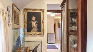 A hallway with a framed portrait, a glass display case with a bird, and a cabinet with glass doors. - Winston Lodge (Beccles)