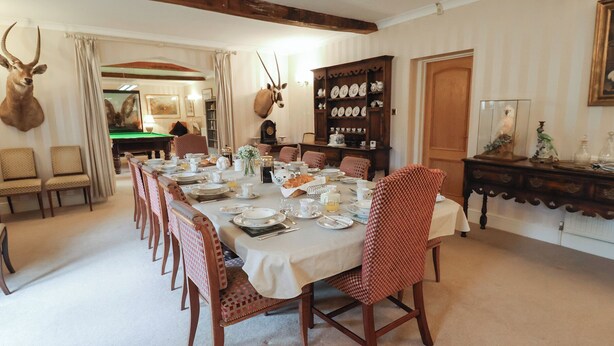 A dining room with a long table set for a meal, surrounded by chairs. - Winston Lodge (Beccles)