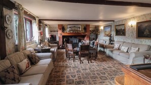 A cozy living room with a fireplace, a dining area, and a sofa set. - Winston Lodge (Beccles)