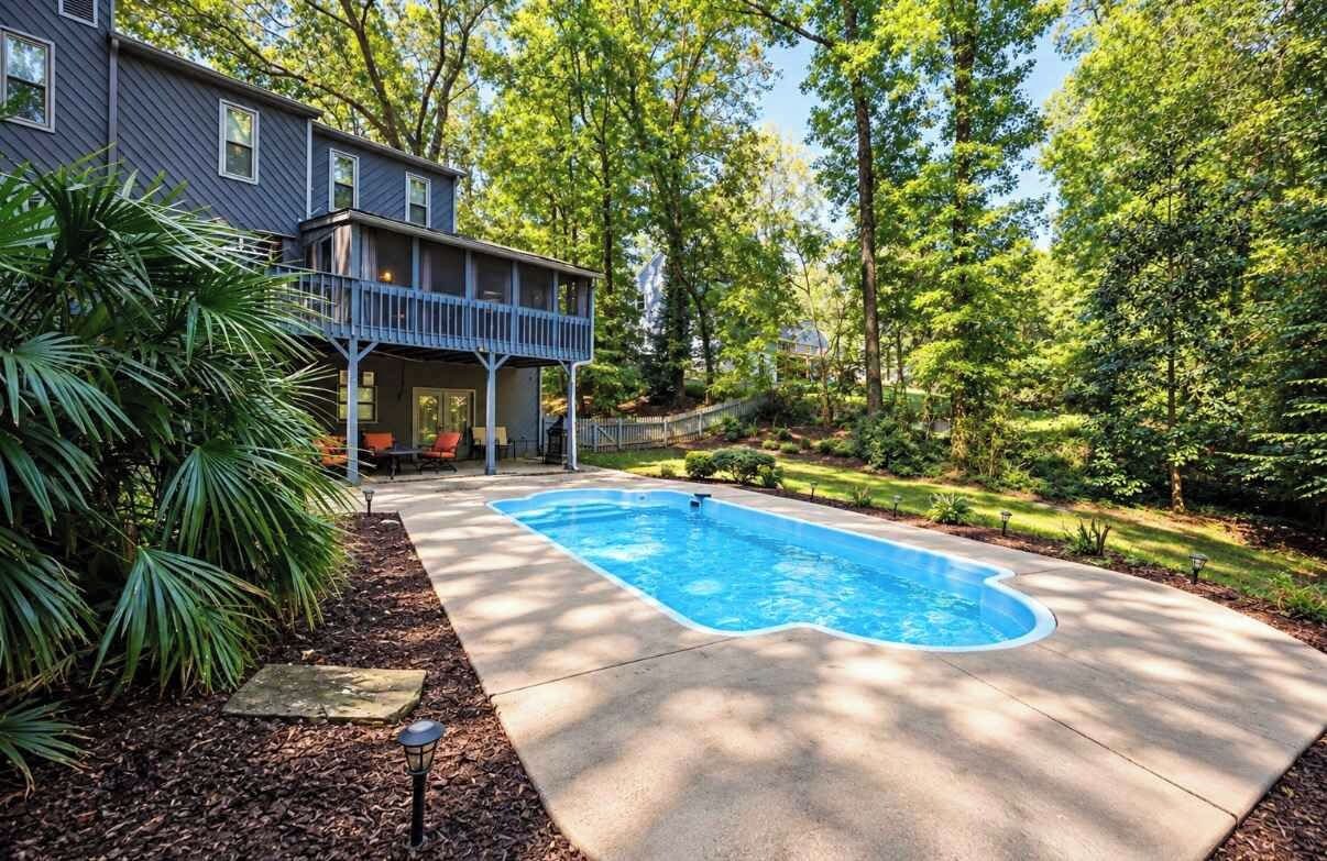 A residential property with a swimming pool, a covered porch, and a well-maintained garden.