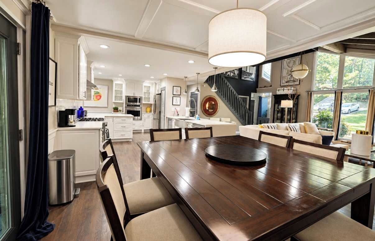 A spacious kitchen with modern appliances, a dining area with a large wooden table, and a staircase leading to an upper level.