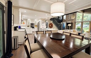 A spacious kitchen with modern appliances, a dining area with a large wooden table, and a staircase leading to an upper level.