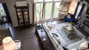 Ein geräumiges Wohnzimmer mit großem Fenster, einer Couch, einem Couchtisch und einer Vitrine.