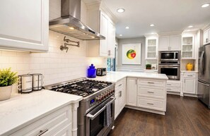 A modern kitchen with white cabinetry, stainless steel appliances, and a central island.
