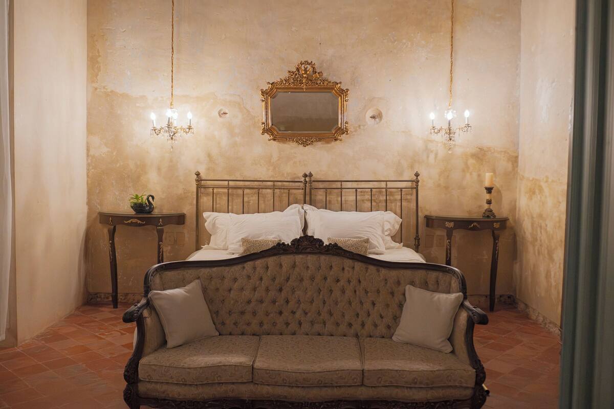 Ein Schlafzimmer mit einem großen Bett, einer Vintage-Couch und zwei Nachttischen mit Lampen.