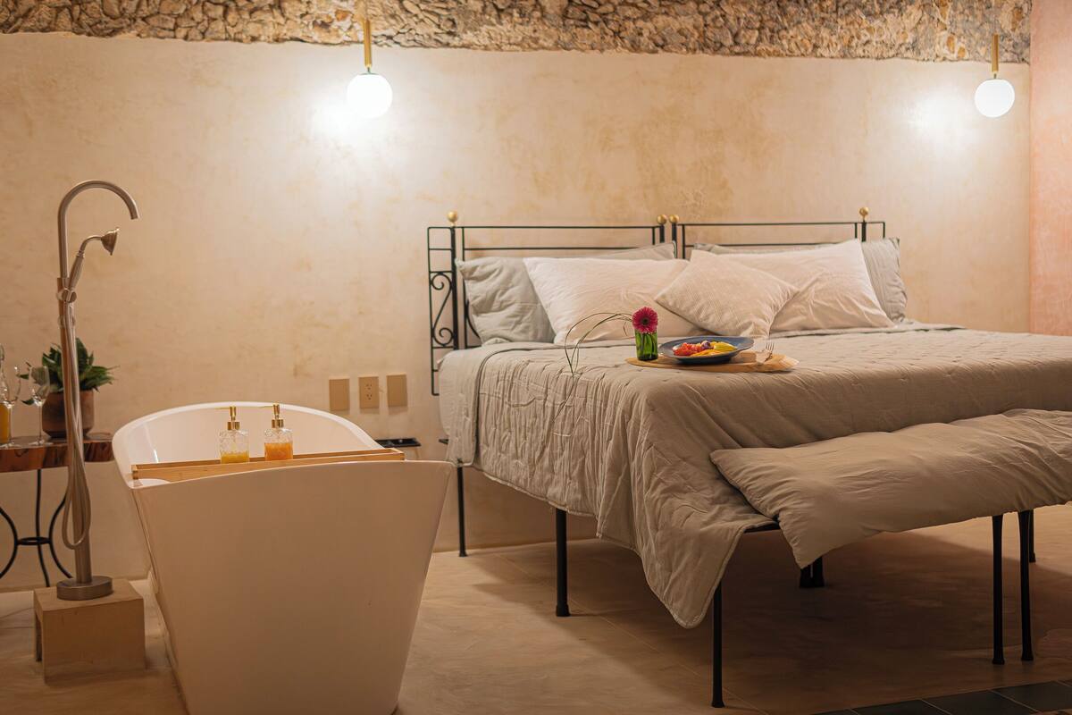 Ein Schlafzimmer mit Bett, Nachttisch und einer Badewanne.