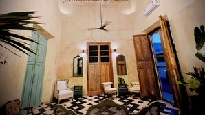 A room with a chandelier, ceiling fan, checkered floor, wooden doors, and a mirror. - Cien Sueños -Experiential Hotel Boutique (Mérida)