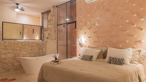 A modern bathroom with a freestanding bathtub, a large mirror, and a stone wall. - Cien Sueños -Experiential Hotel Boutique (Mérida)