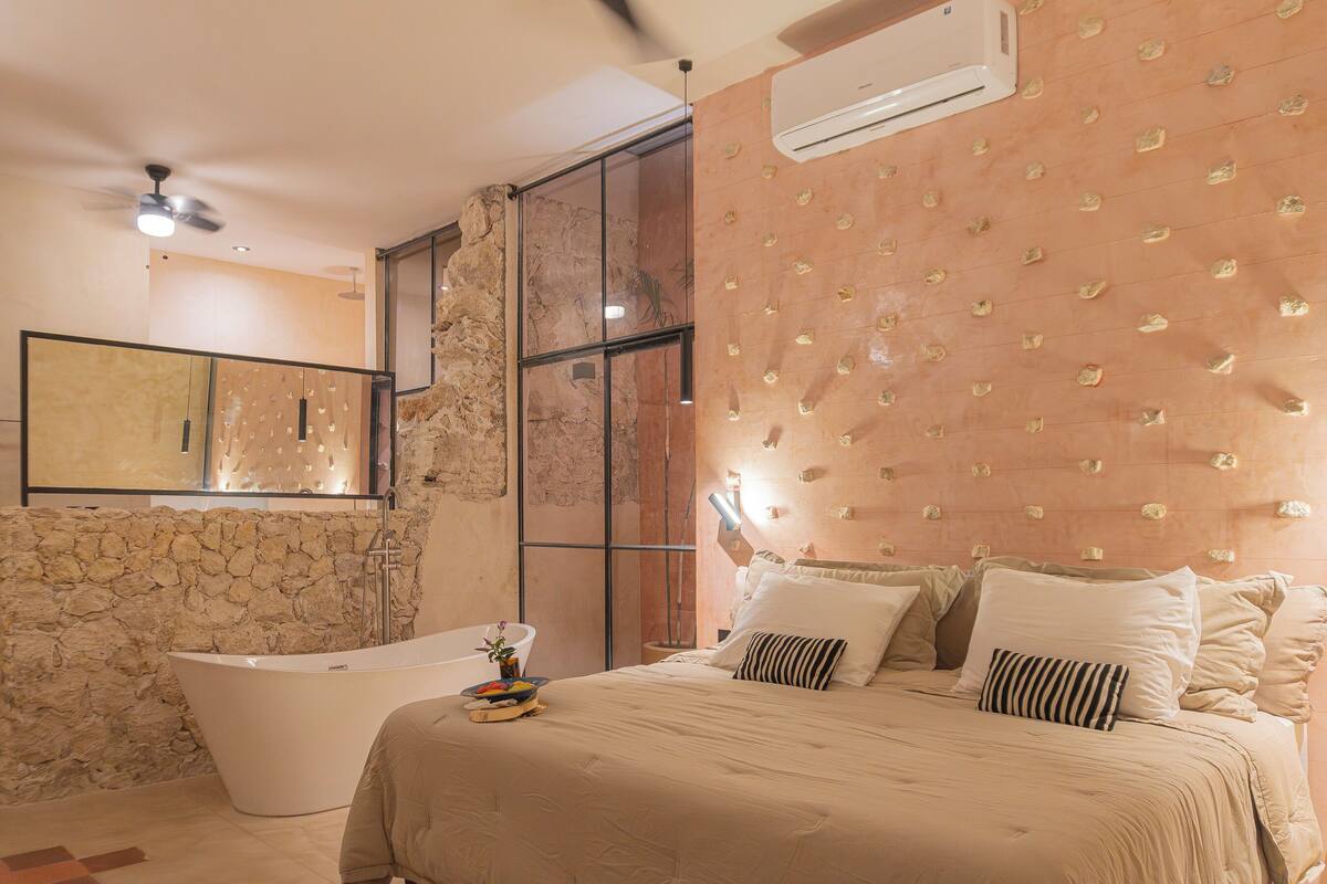 Ein modernes Badezimmer mit einer freistehenden Badewanne, einem großen Spiegel und einer Steinwand.