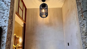 A hallway with a patterned floor, a hanging light fixture, and a potted plant. - Cien Sueños -Experiential Hotel Boutique (Mérida)