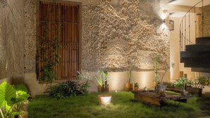 A courtyard with a stone wall, potted plants, and a wooden bench. - Cien Sueños -Experiential Hotel Boutique (Mérida)