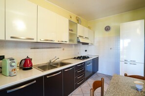 Une cuisine de taille réduite, avec des meubles blancs, une cuisinière à gaz, un évier et un grille-pain.