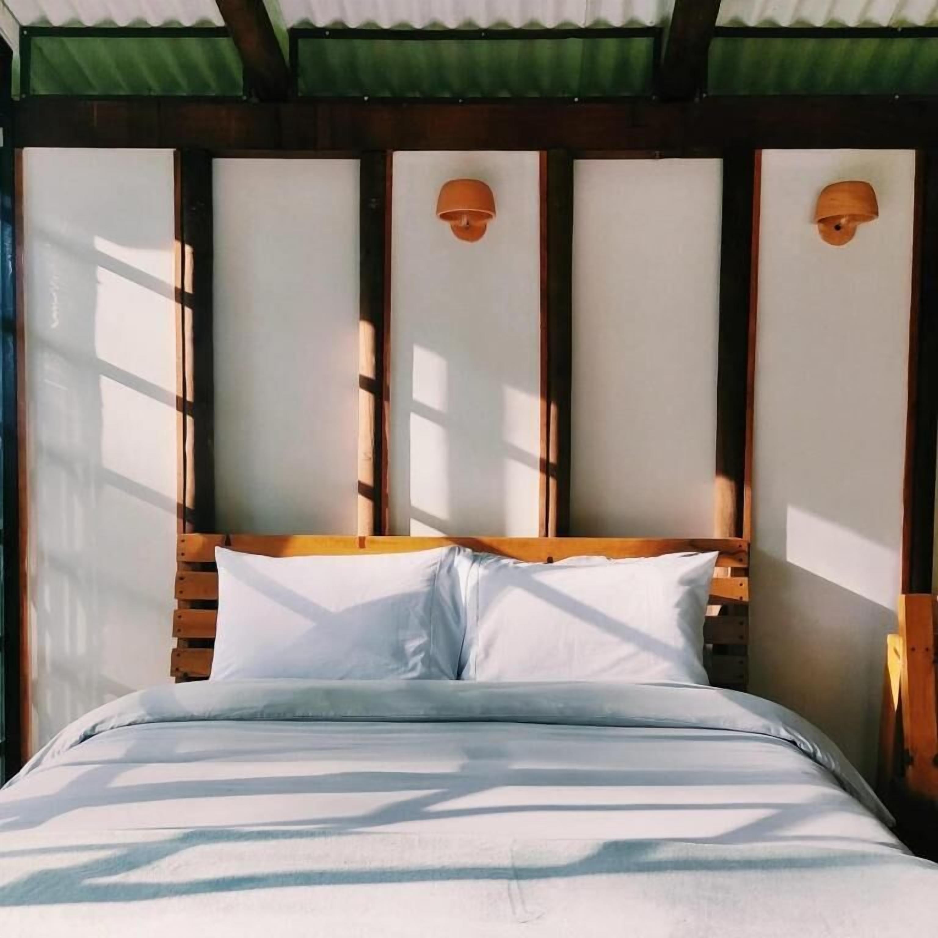 A bed with a wooden headboard and white bedding, under a green roofed structure.
