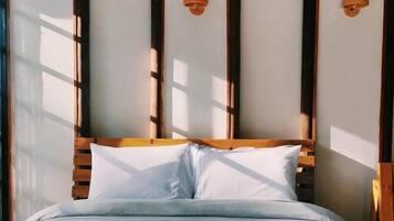 A bed with a wooden headboard and white bedding, under a green roofed structure.