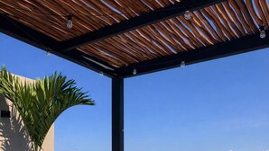 Ett bubbelbad med fri utsikt över havet och en träpergola ovanför.