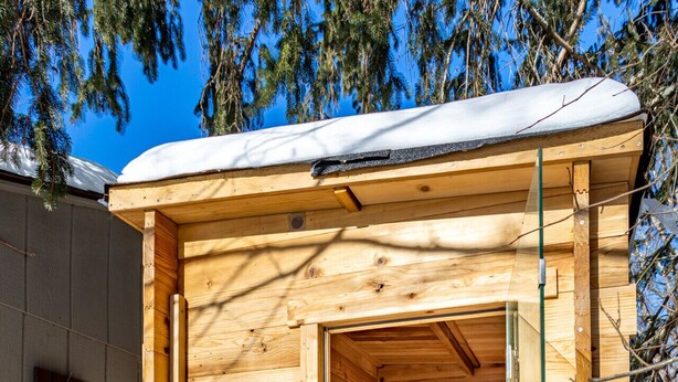 A wooden sauna structure with a bench and a table inside, surrounded by snow. - NEW: In-town home w/ gorgeous cedar sauna+fire-pit (Livingston Manor)
