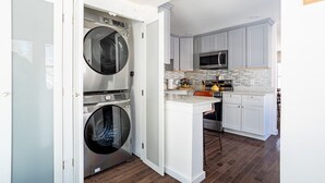A compact kitchen with a built-in washer and dryer, a microwave, and a small island with seating. - NEW: In-town home w/ gorgeous cedar sauna+fire-pit (Livingston Manor)
