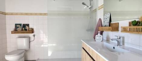 A modern bathroom with a wooden vanity, a toilet, and a shower.