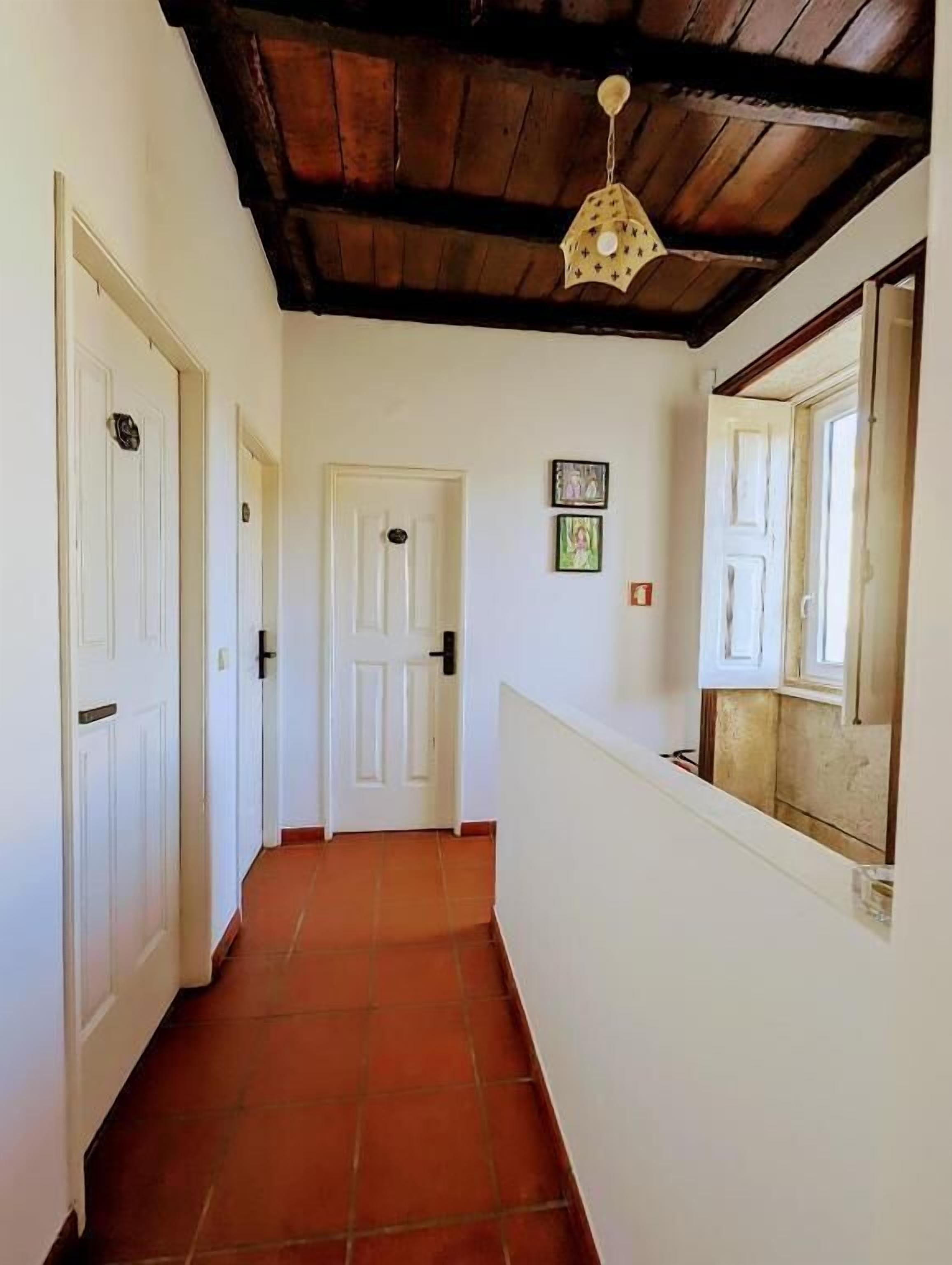A hallway with white doors, a tiled floor, and a wooden ceiling.