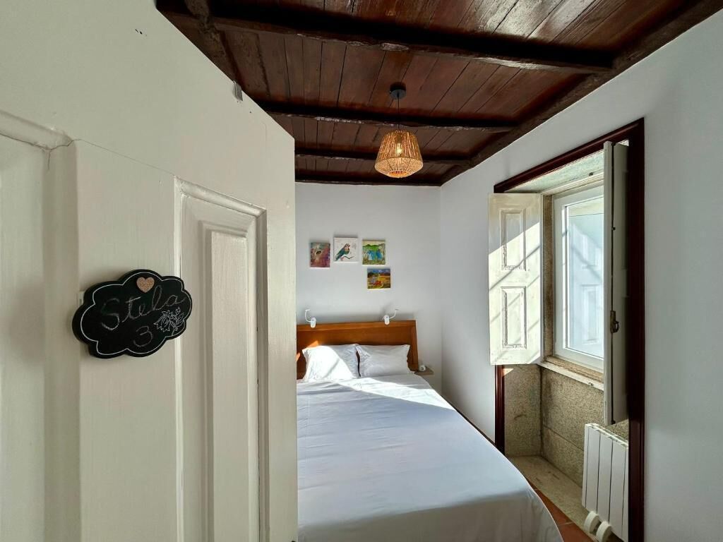 A bedroom with a bed, a wooden ceiling, a hanging light fixture, and a door with a sign.