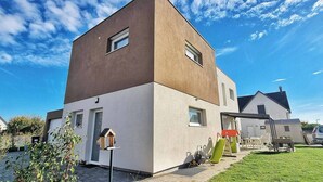 A modern two-story house with a flat roof, a small front porch, and a visible window. - Charming air-conditioned duplex with terrace - Near the Rhine Ring & Colmar (Niederentzen)