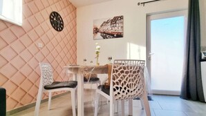 A dining area with a table and chairs, a clock, a framed picture, and a door with a view. - Charming air-conditioned duplex with terrace - Near the Rhine Ring & Colmar (Niederentzen)