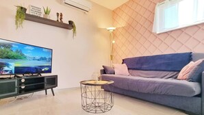 A modern living room with a flat-screen TV, a sofa, a coffee table, and a wall-mounted air conditioner. - Charming air-conditioned duplex with terrace - Near the Rhine Ring & Colmar (Niederentzen)