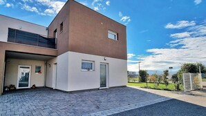 A modern two-story building with a flat roof, a balcony on the upper floor, and a paved entrance area. - Charming air-conditioned duplex with terrace - Near the Rhine Ring & Colmar (Niederentzen)