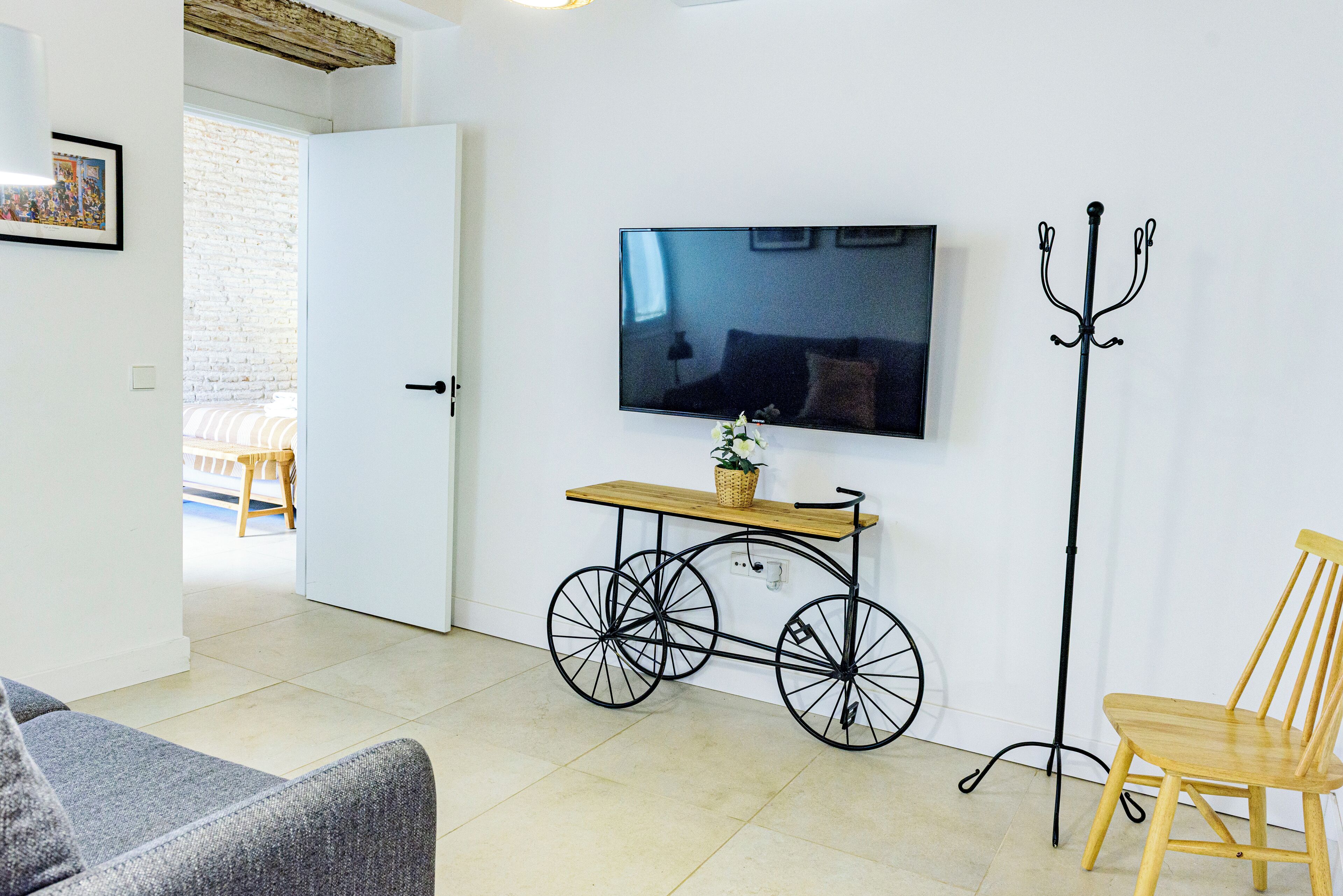 Un salon comprenant un téléviseur, une chaise en bois, un banc et une table en forme de vélo.