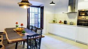 A modern kitchen with white cabinets, a built-in oven, and a dining area with a wooden table and chairs. - Elegant pet-friendly family home in Santa Cruz, near the Cathedral (Sevilla)