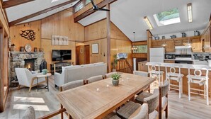 Uma sala de estar ampla com lareira, assentos e uma cozinha com armários de madeira e uma ilha grande.