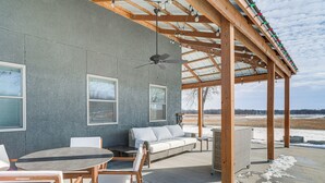 Ulkoterassi, jossa on puinen pergola, kattotuuletin sekä oleskelualue, johon kuuluu sohva ja tuoleja.
