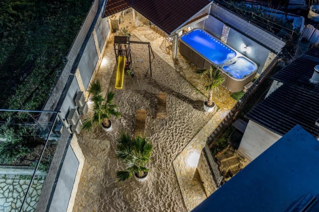 Luftaufnahme einer Dachterrasse mit Whirlpool, Rutsche und Palmen.