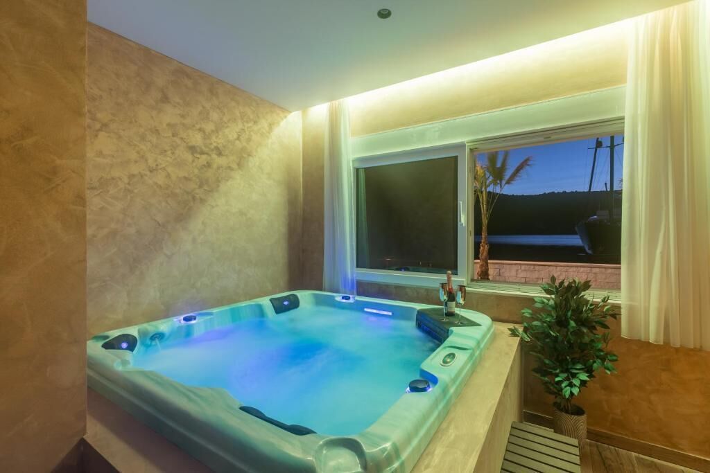 A hot tub in a room with a window, a plant, and a view of the outside.