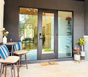 Un patio moderno con puerta de cristal, cojines a rayas y plantas en macetas.