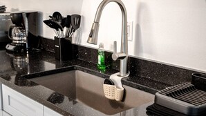 A kitchen with a stainless steel faucet, a coffee maker, and a utensil holder. - Family Fun Barn - Pet Friendly (Hot Springs)