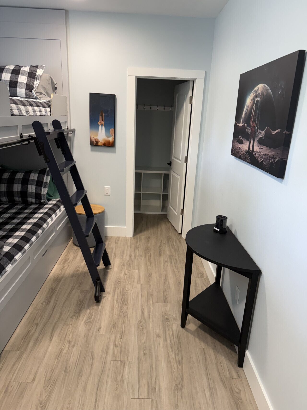 Een kamer met een stapelbed, een ladder, een klein tafeltje en een deur naar een inloopkast.
