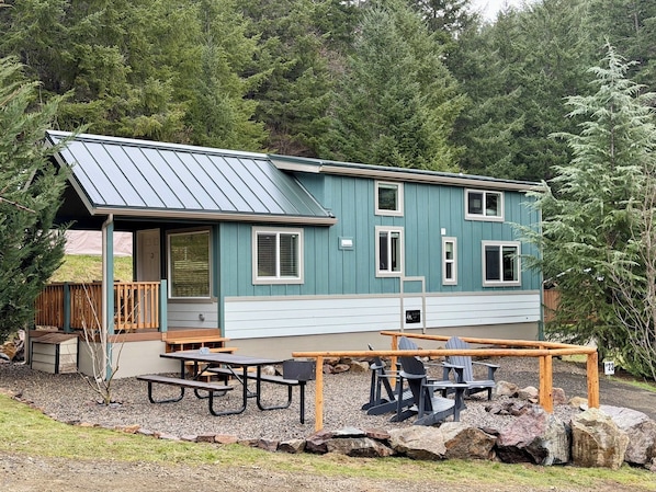 A two-story building with a covered patio area, picnic tables, and Adirondack chairs.