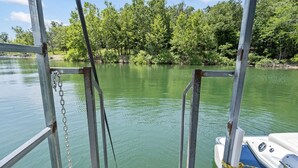A dock with a boat tied to it, surrounded by calm water and dense greenery. - One of our three large two bedroom “A” frame cabins at the Bar M Resort on Table Rock Lake (Branson)