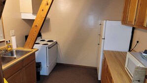 A compact kitchen with a stove, sink, and refrigerator. - One of our three large two bedroom “A” frame cabins at the Bar M Resort on Table Rock Lake (Branson)