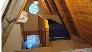 A small attic bedroom with a sloped ceiling, a bed, a ceiling fan, and a skylight. - One of our three large two bedroom “A” frame cabins at the Bar M Resort on Table Rock Lake (Branson)