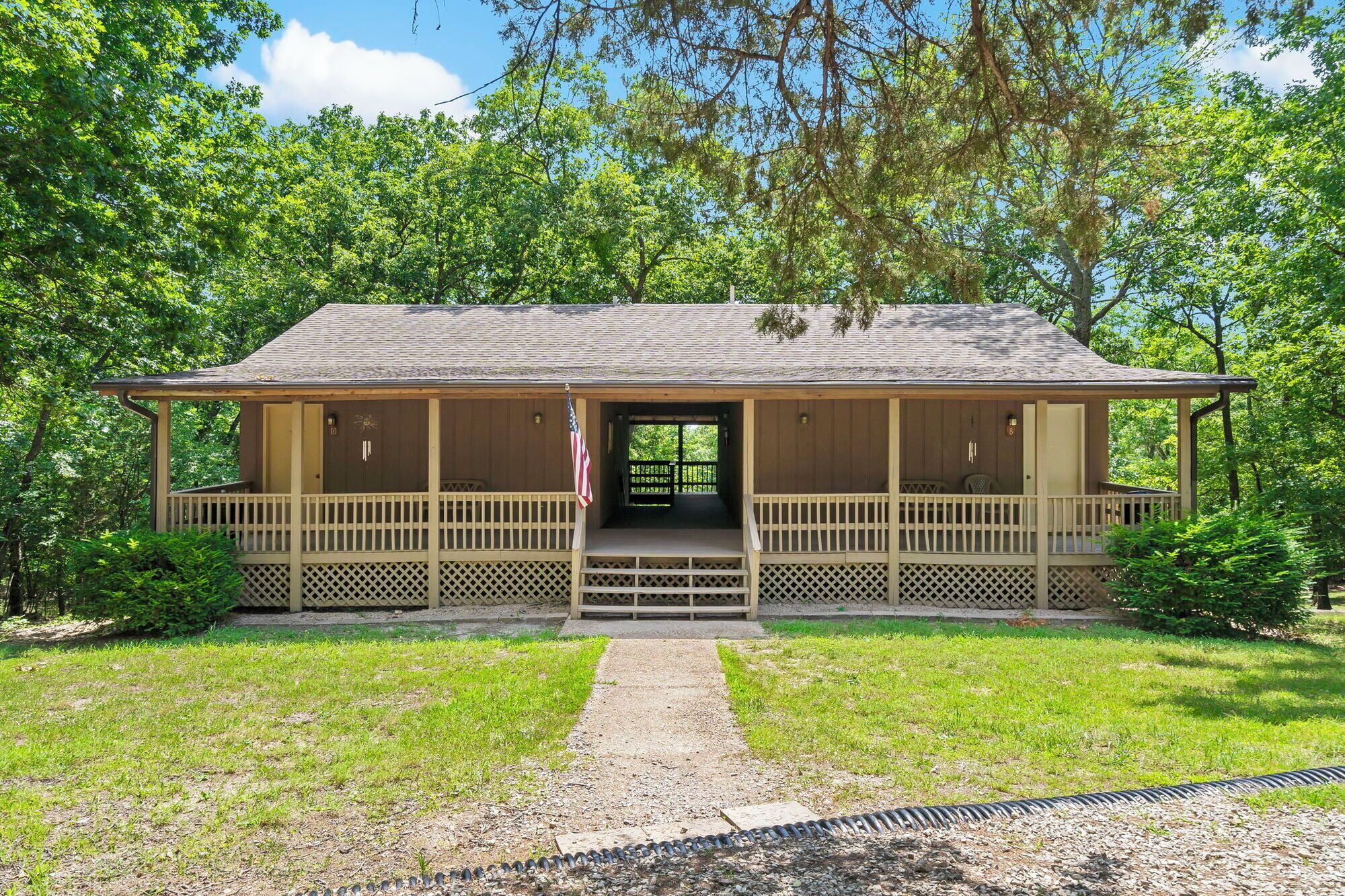 A wooden cabin with a porch, a front door, and a small set of stairs leading up to the entrance.