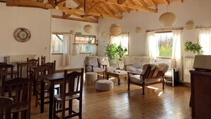 A spacious room with wooden beams on the ceiling, a dining area with wooden chairs, a sofa, and a coffee table. - Hosteria Hainen Cabins, located in El Calafate, 10 minutes from downtown. (El Calafate)