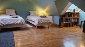 Ein gemütliches Schlafzimmer im Dachgeschoss mit zwei Betten, einer Holzbibliothek und einem Oberlicht.