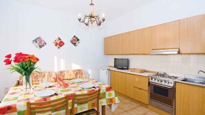 Una cucina compatta con mobili in legno, un piano cottura a gas e una piccola televisione.