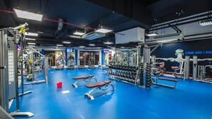 Un gimnasio con diversos equipos de ejercicio, bancos y mancuernas.