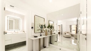 Un baño moderno con un espejo grande, encimeras de mármol blanco y un mueble de tocador.