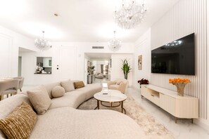 A modern living room with a sectional sofa, a round coffee table, and a TV mounted on the wall. - Stayshort - Modern 4 Bed Apartment in JBR That Sleeps 8 (Dubai)