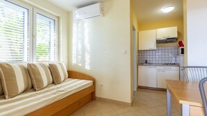 A compact living space with a sofa, a dining table, and a kitchenette. - Standard One Bedroom Apartment with Sea View and Terrace (Stanici)
