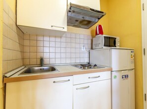 Eine kleine Küche mit Spüle, Mikrowelle und Kühlschrank.